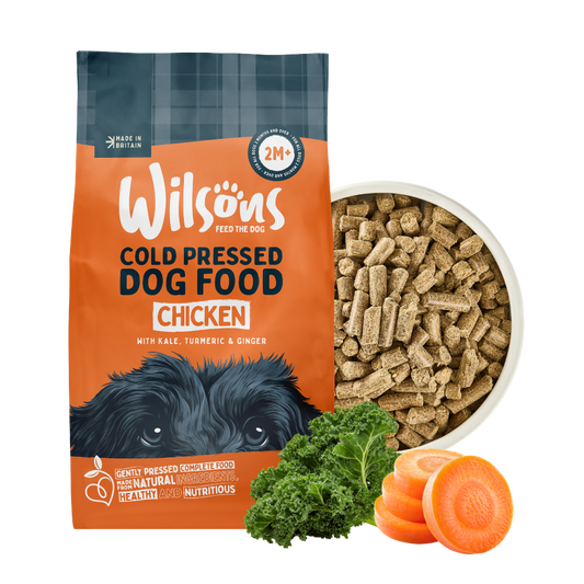 Wilsons cold pressed chicken dog food bag beside a bowl of the food with kale and carrot