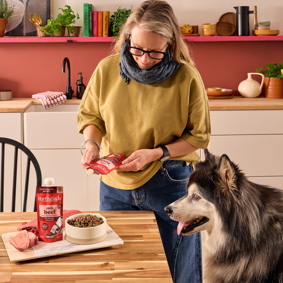 Forthglade rich beef bone broth topper being poured over dry food for a dog