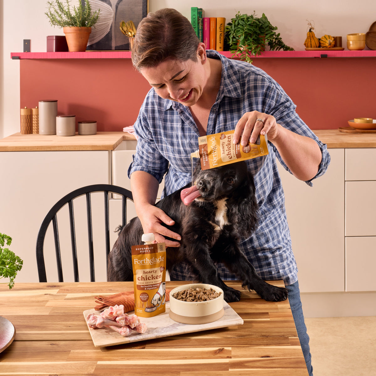 Forthglade hearty chicken bone broth topper being poured over dry food for a dog