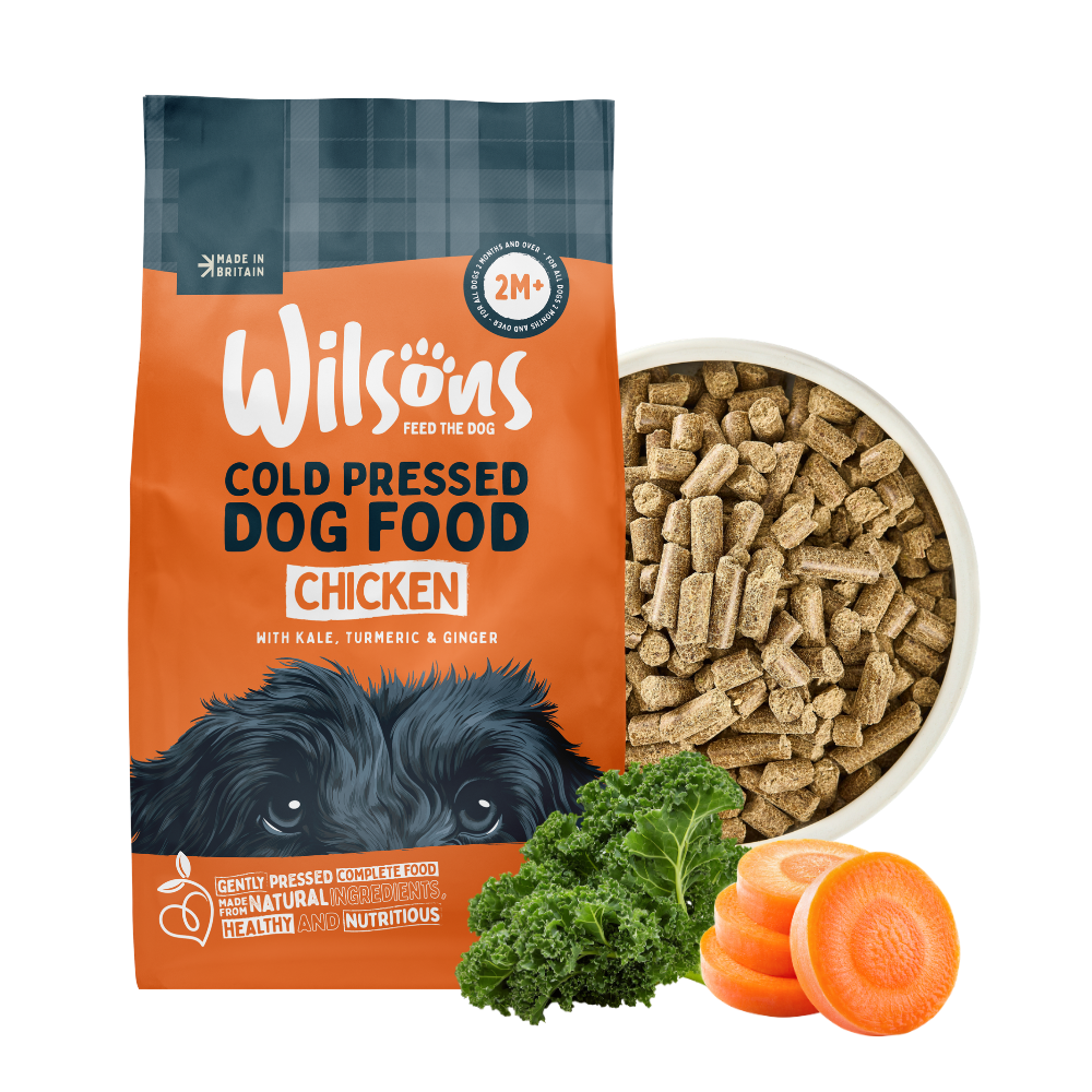 Wilsons cold pressed chicken dog food bag beside a bowl of the food with kale and carrot