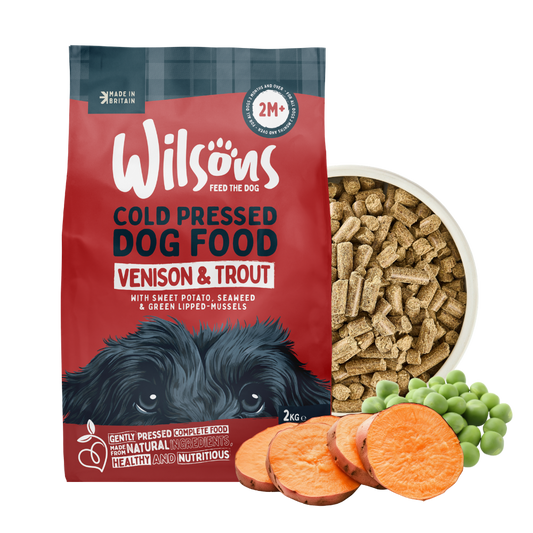 Wilsons cold pressed venison and trout dog food bag beside a bowl of the food with sweet potato and peas
